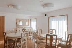 A dining area with round tables and wooden chairs, a mirror on the wall, and large windows with sheer curtains. - Quinta do Fontelo (Vouzela)