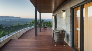 A wooden deck with a glass table and chairs, overlooking a mountainous landscape. - Quinta do Fontelo (Vouzela)