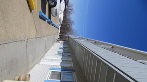A corridor with a concrete floor, a white railing, and a blue railing on the right side. - Adair Budget Inn (Adair)