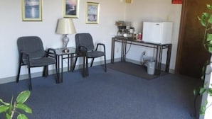 A conference room with a table and chairs, a whiteboard, and framed pictures on the wall. - Adair Budget Inn (Adair)