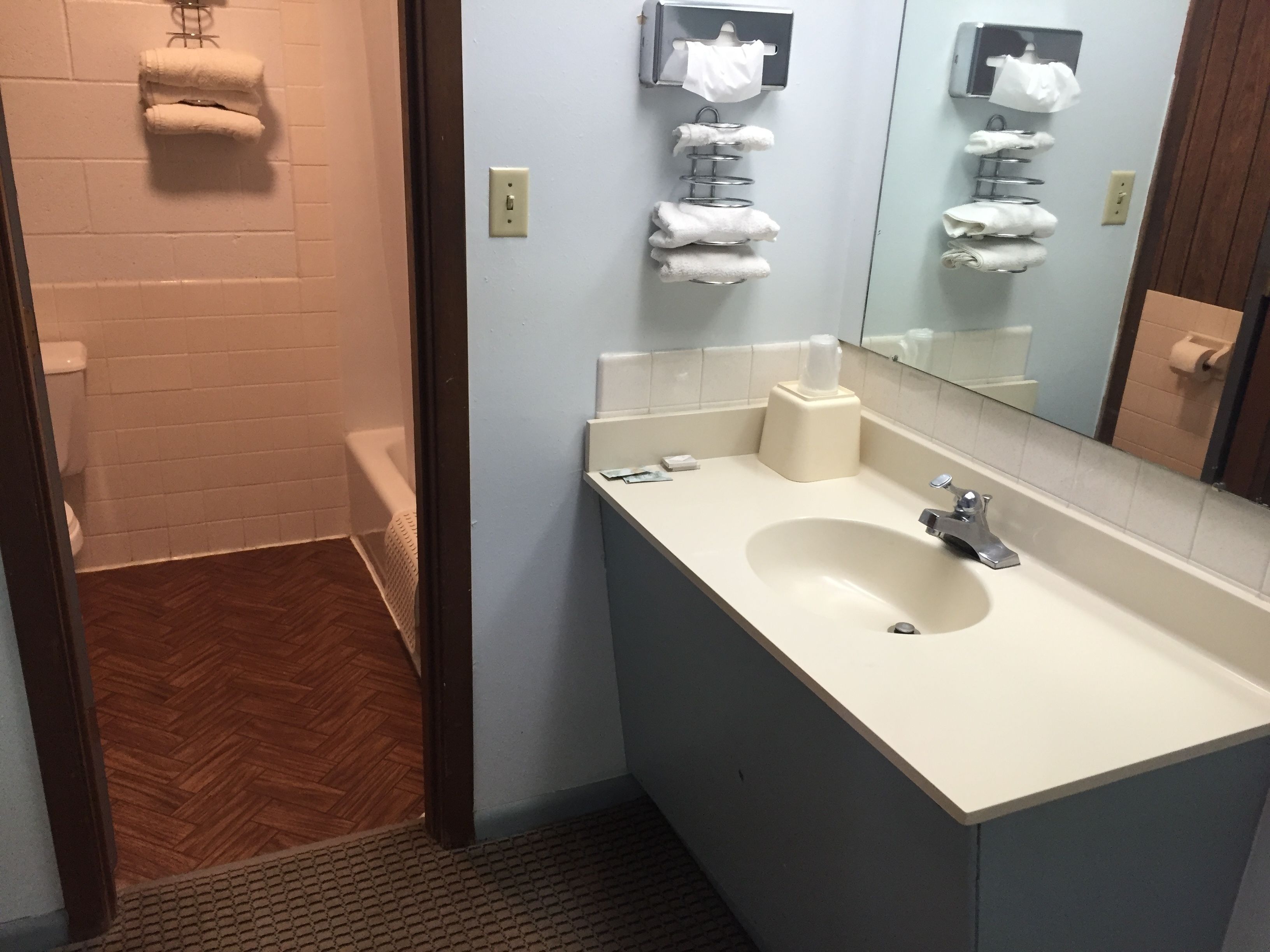 A bathroom with a sink, mirror, towel rack, and toilet.