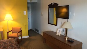 A hotel room with a bed, a chair, a desk, a television, and a lamp. - Adair Budget Inn (Adair)