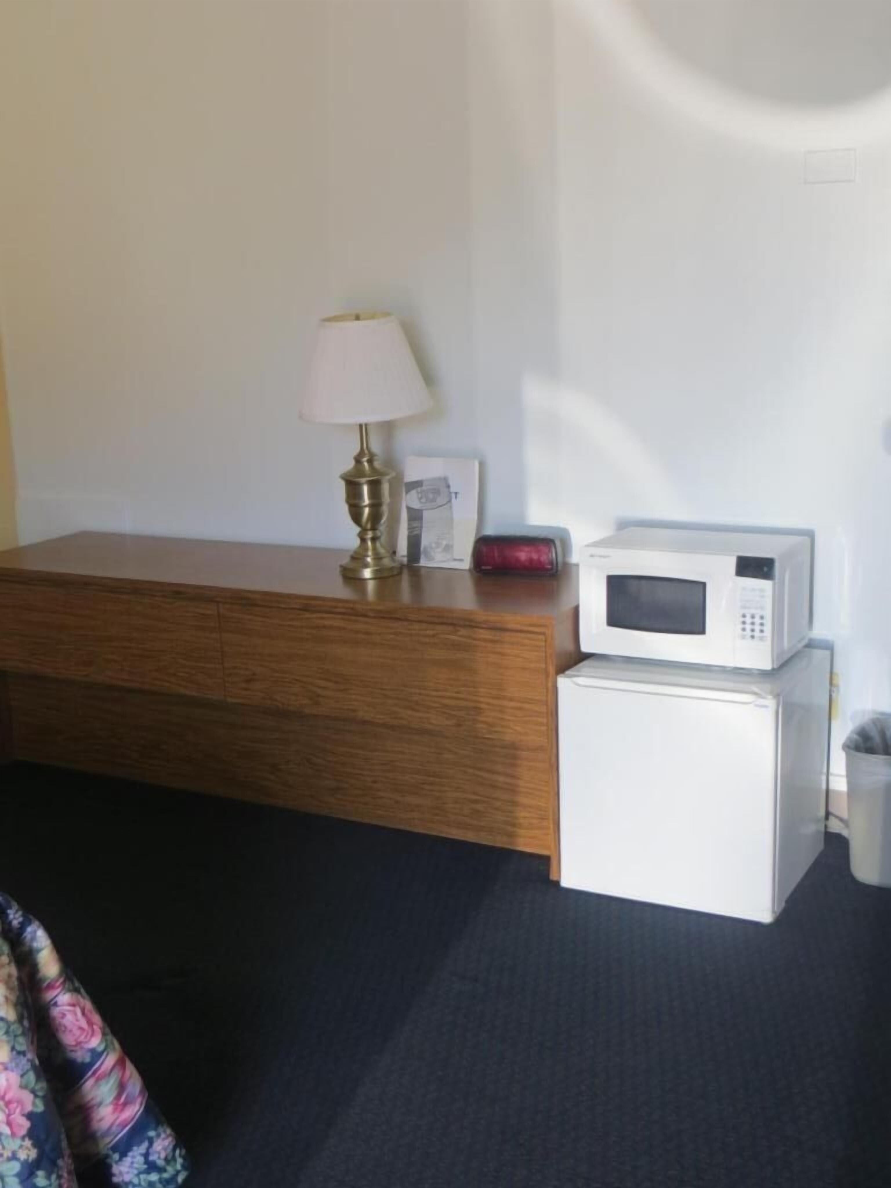 A bathroom with a wooden cabinet, a white toilet, a white sink, and a white microwave.