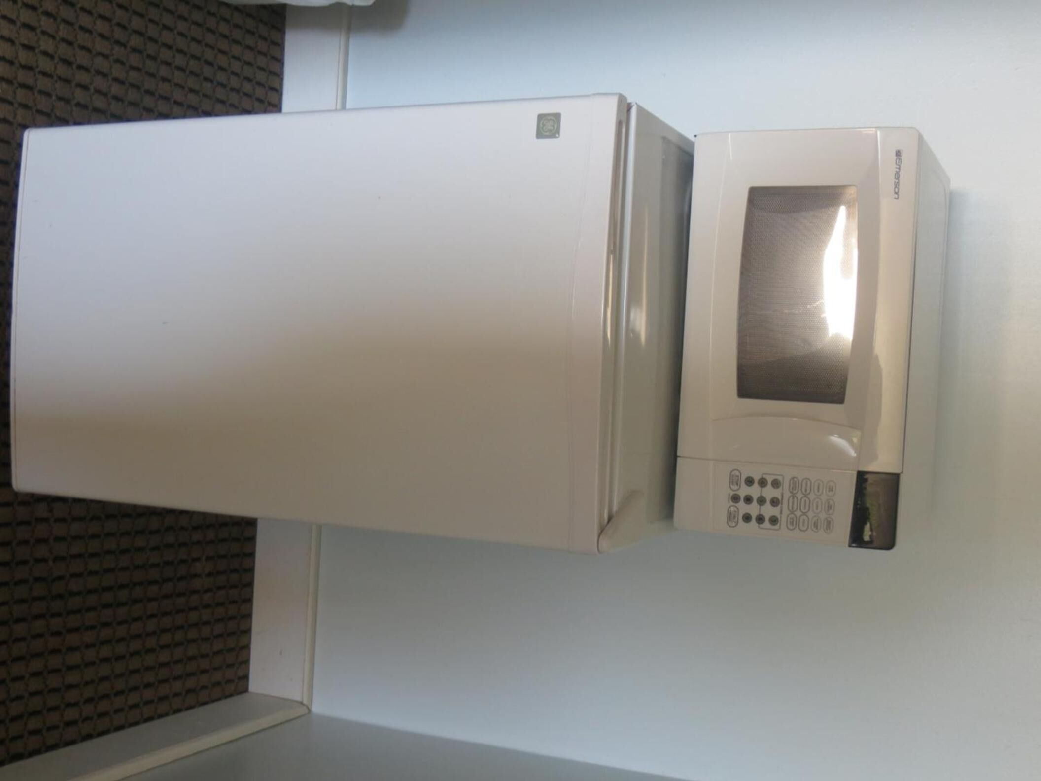 Un four à micro-ondes blanc fixé au mur et un réfrigérateur blanc.