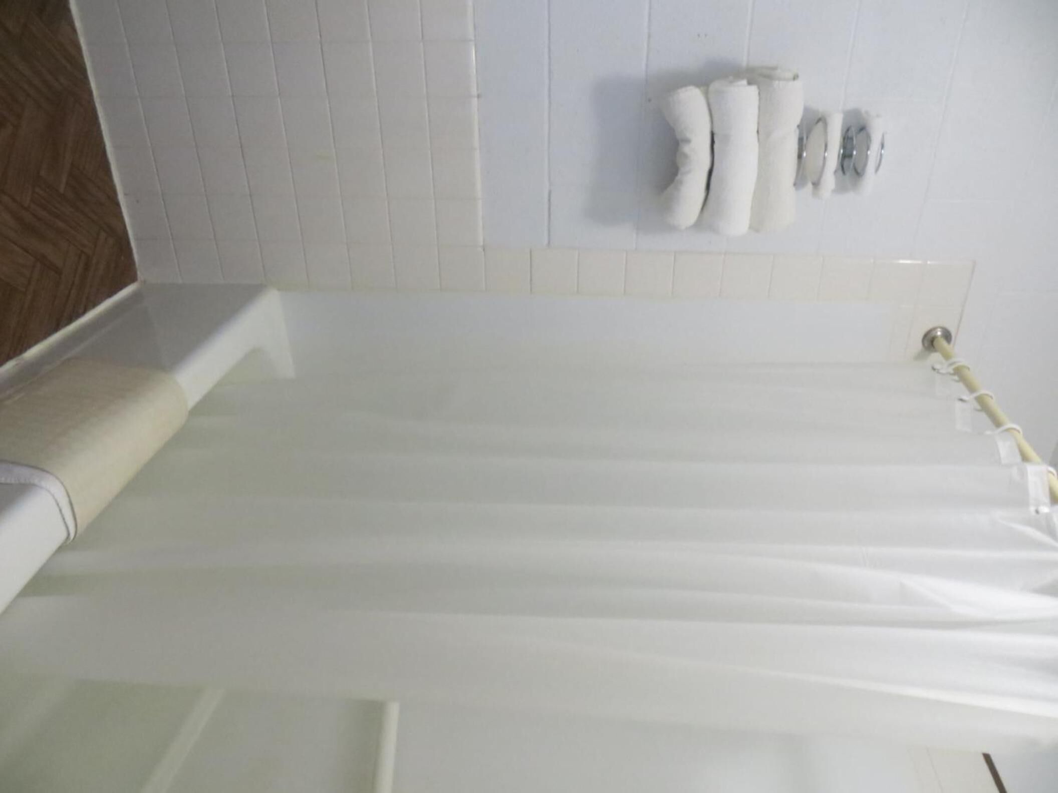 Un baño con una bañera blanca, un perchero con toallas y un inodoro.
