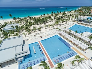 A resort with a large pool, beach, and palm trees.