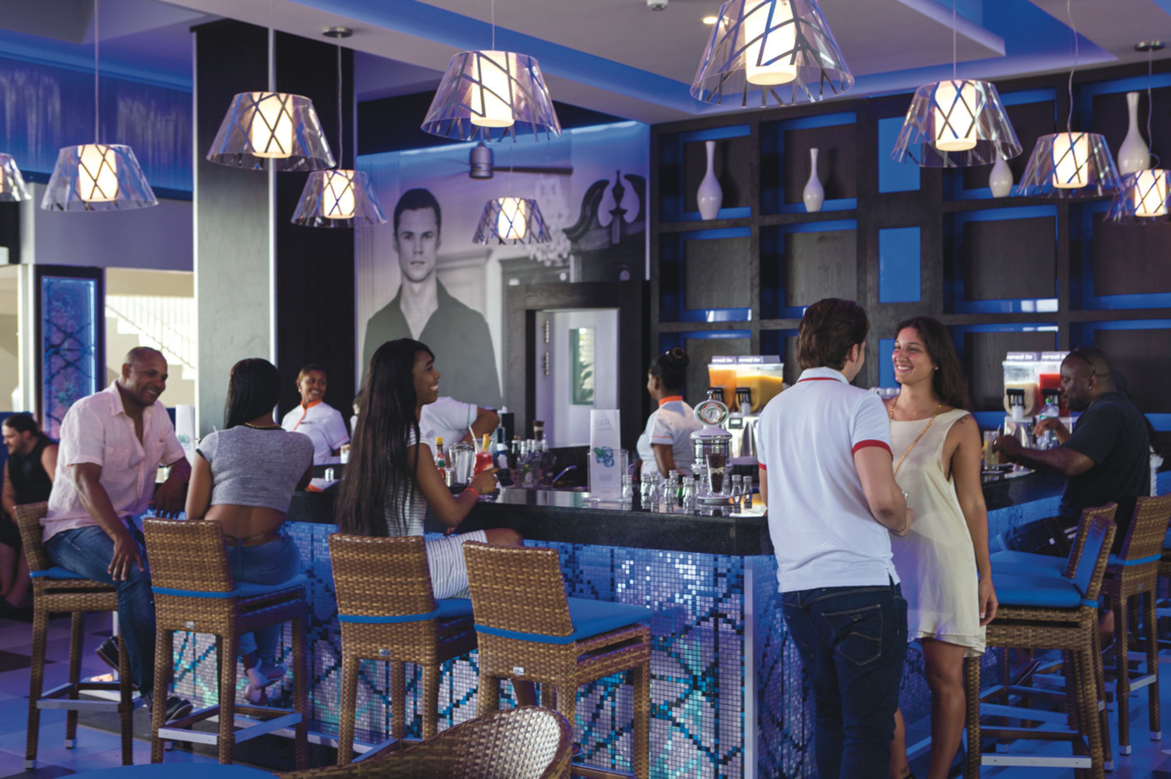 A bar area with wicker chairs, a counter, and hanging pendant lights.