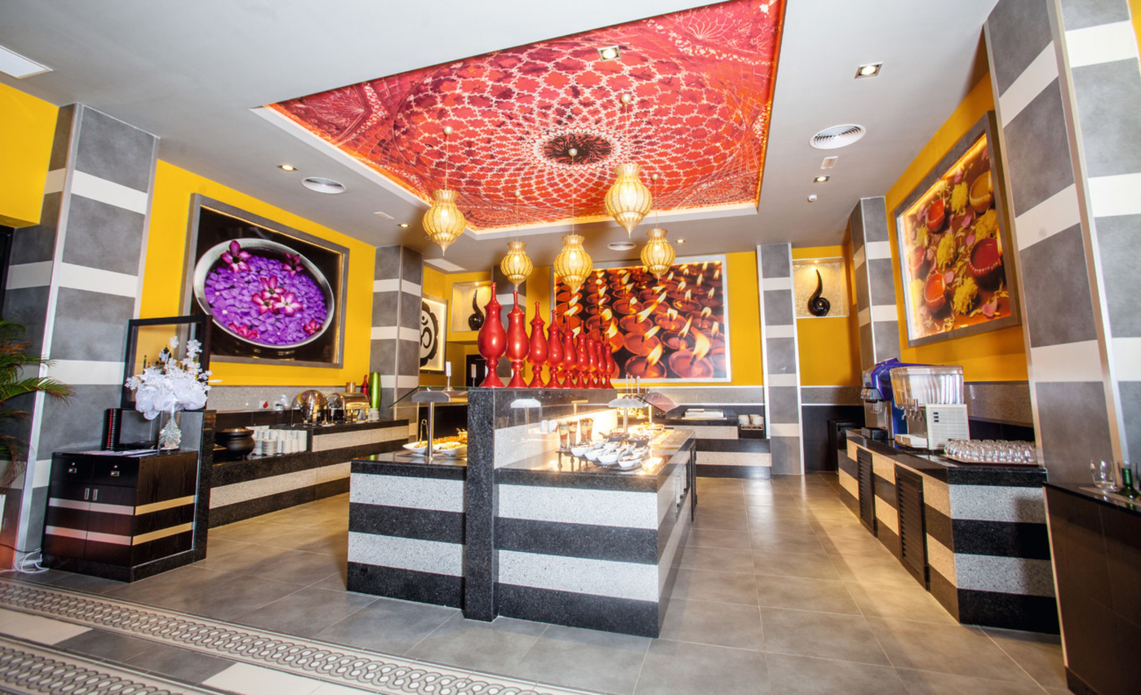A modern hotel lobby with a central island, decorative vases, and a patterned ceiling.