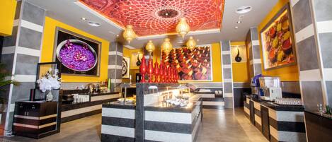 A modern hotel lobby with a central island, decorative vases, and a patterned ceiling.