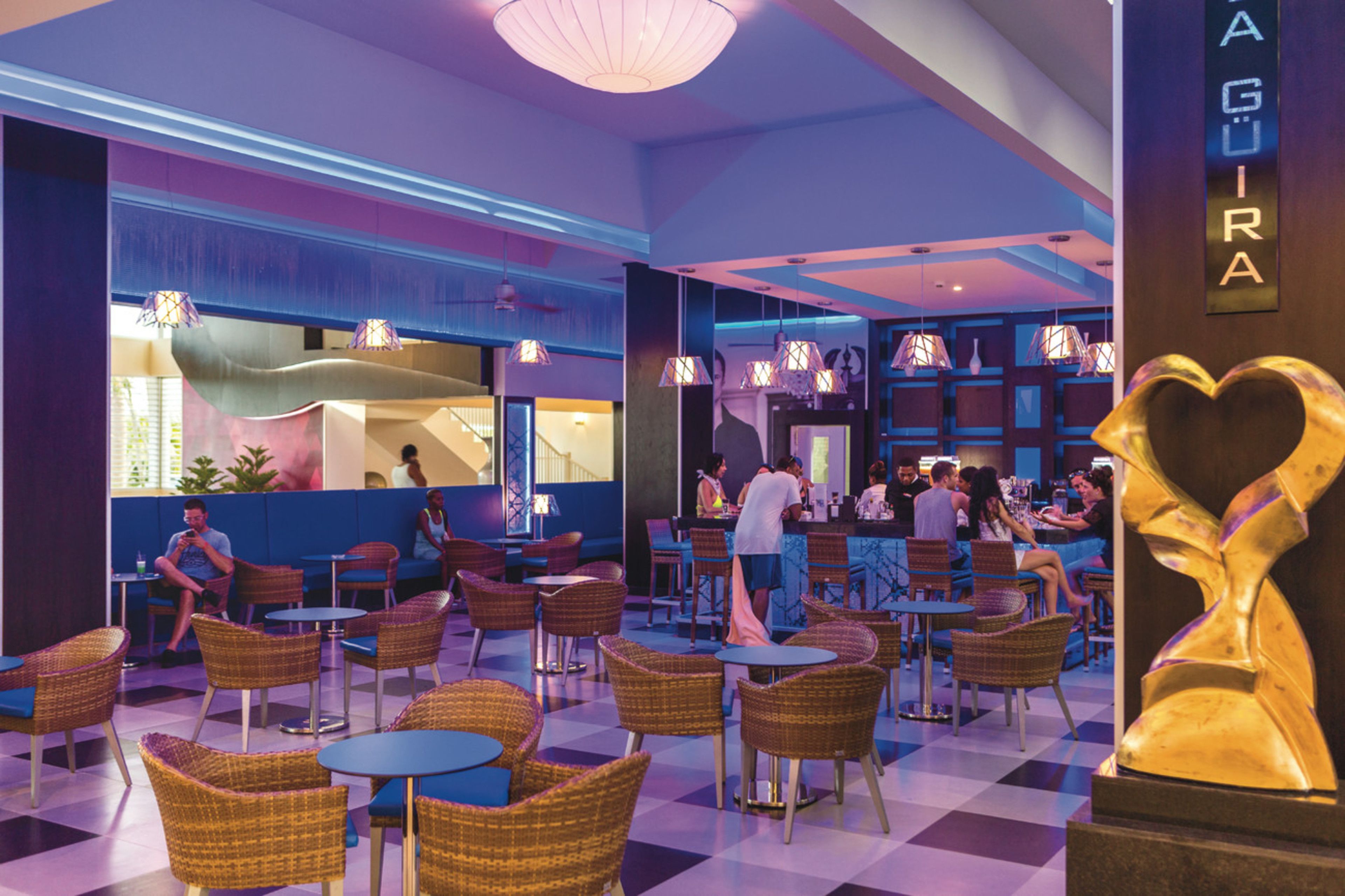 A spacious indoor area with wicker chairs and tables, a bar area, and a visible restaurant section.