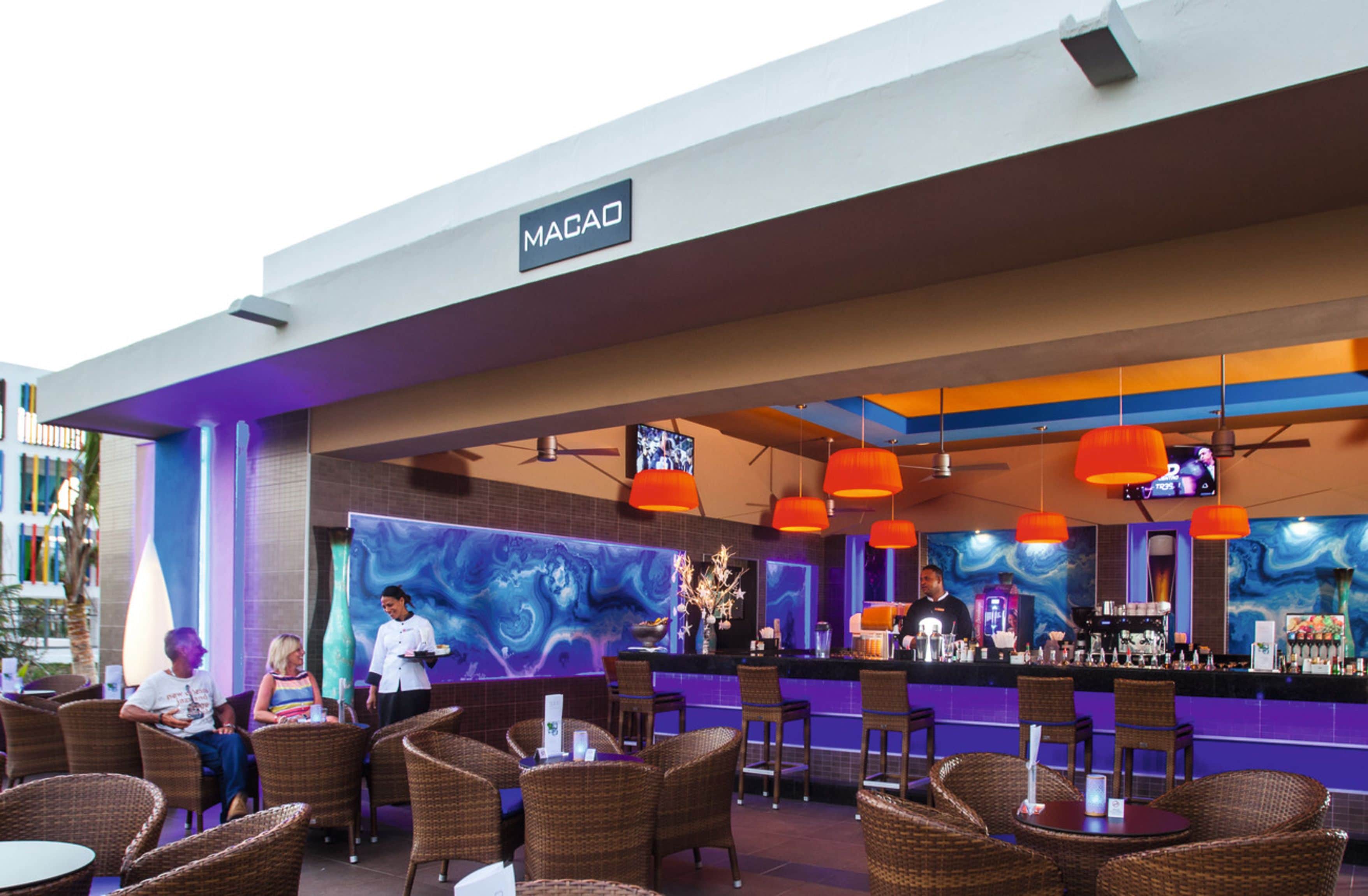 An outdoor bar area with wicker furniture and a colorful mural.