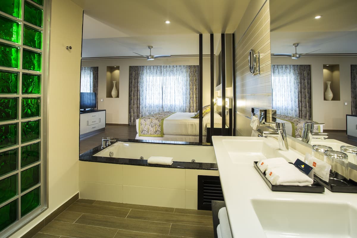 A modern hotel bathroom with a large mirror, a bathtub, and a vanity with a sink and towel rack.