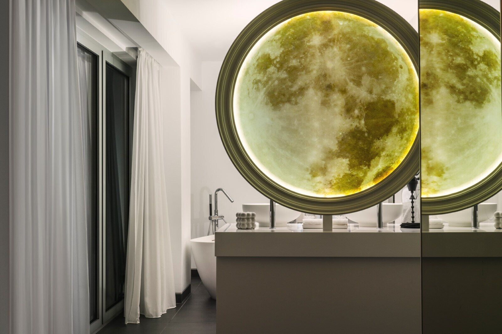 A modern bathroom with a large round mirror, a sink, and a toilet.