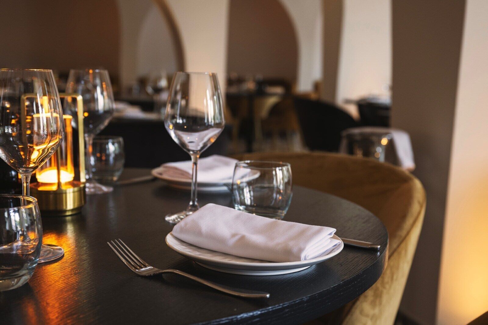 Una mesa de comedor preparada con copas de vino, un mantel doblado y cubiertos.