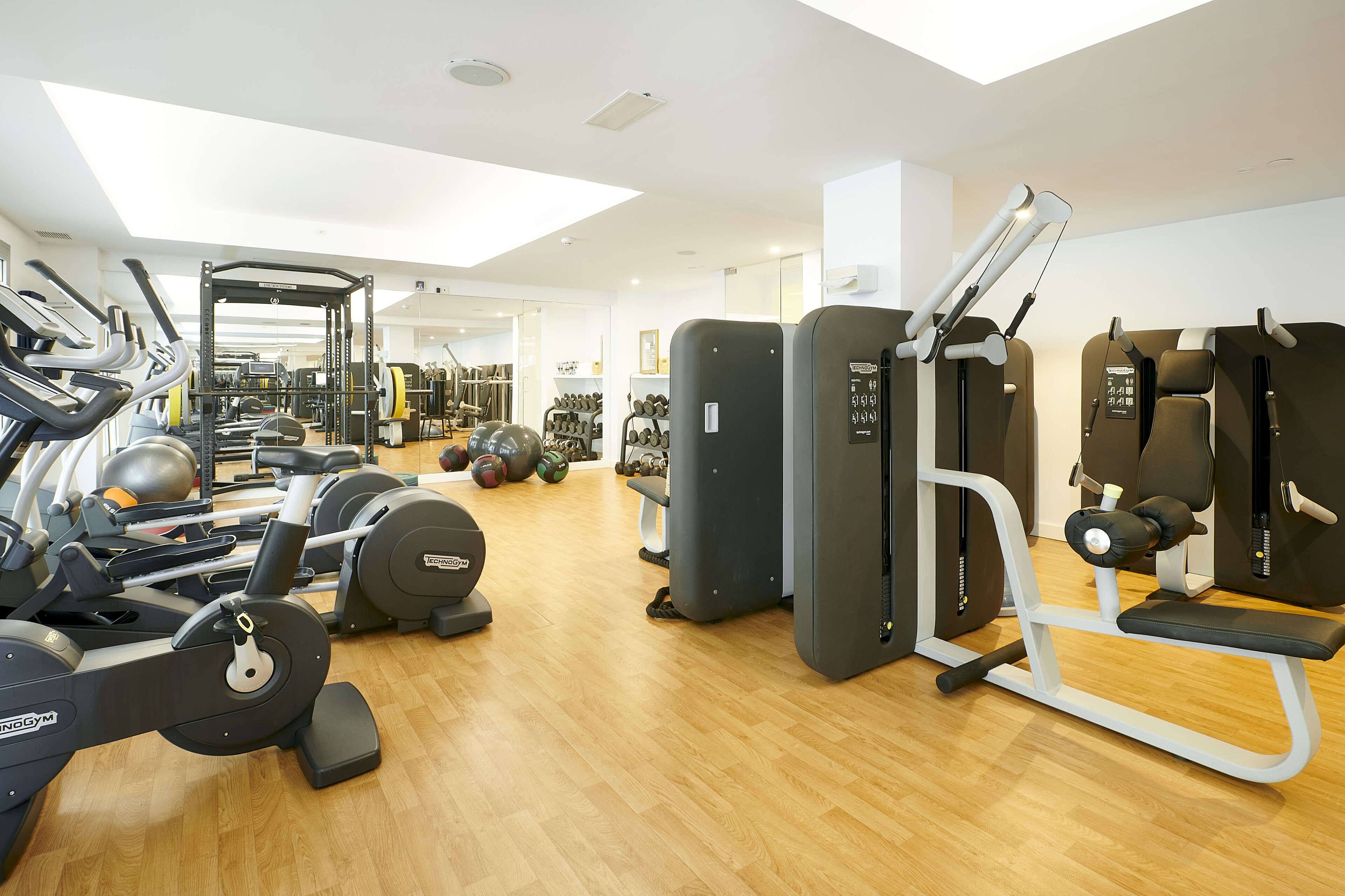 A gym with cardio machines, weightlifting equipment, and a variety of dumbbells and exercise balls.