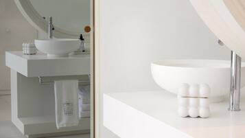 A modern bathroom with a white sink, a large mirror, and a towel rack.
