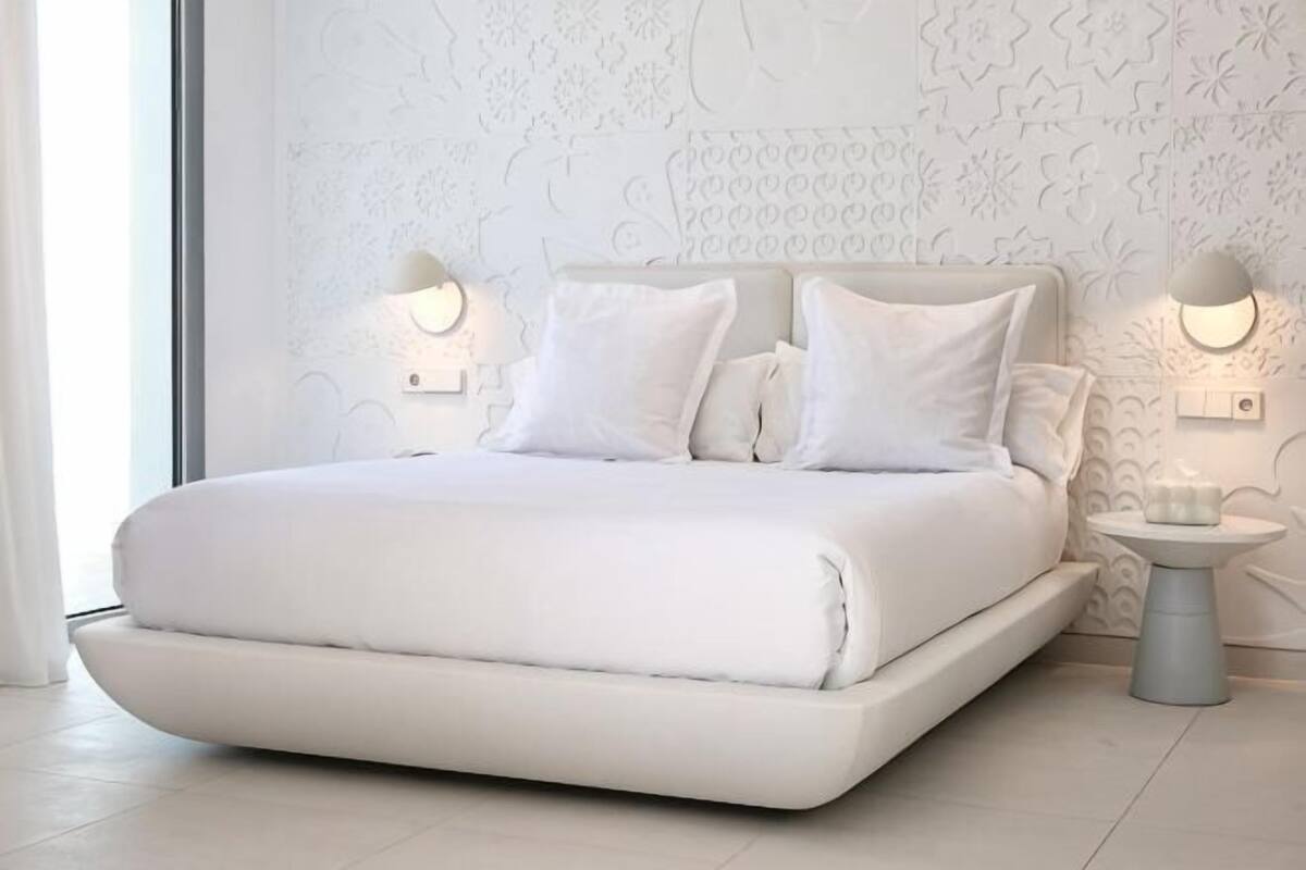 A modern bedroom with a large bed, two bedside lamps, and a small table.
