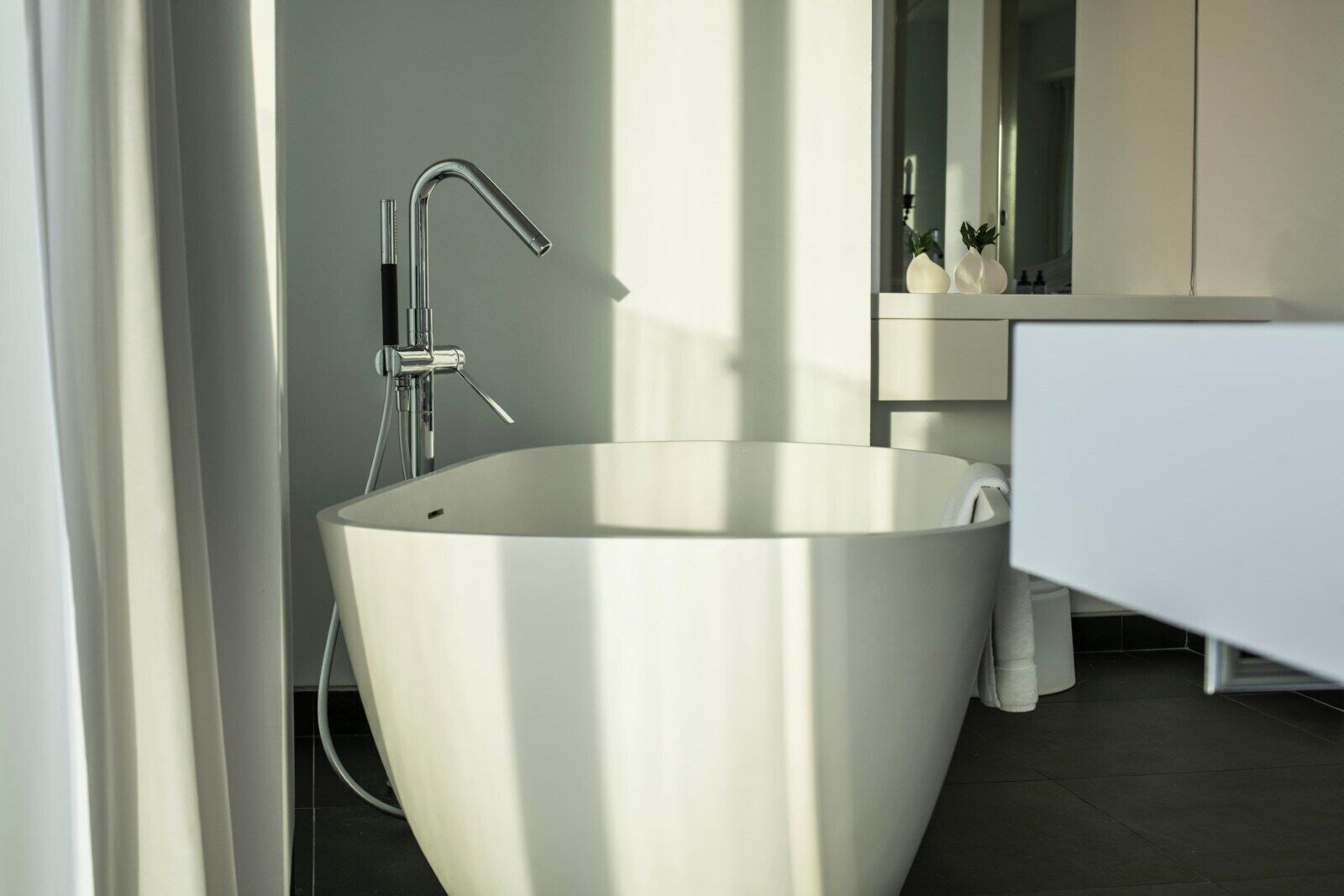 A modern bathroom with a freestanding bathtub, a sleek faucet, and a minimalist vanity.