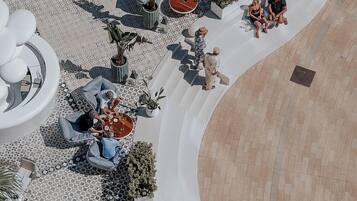 An outdoor patio area with seating arrangements, potted plants, and a curved pathway.