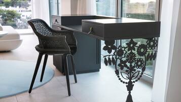 A modern office space with a desk, two chairs, and a decorative metal railing with floral patterns.