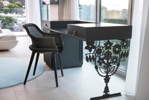A modern office space with a desk, two chairs, and a decorative metal railing with floral patterns.