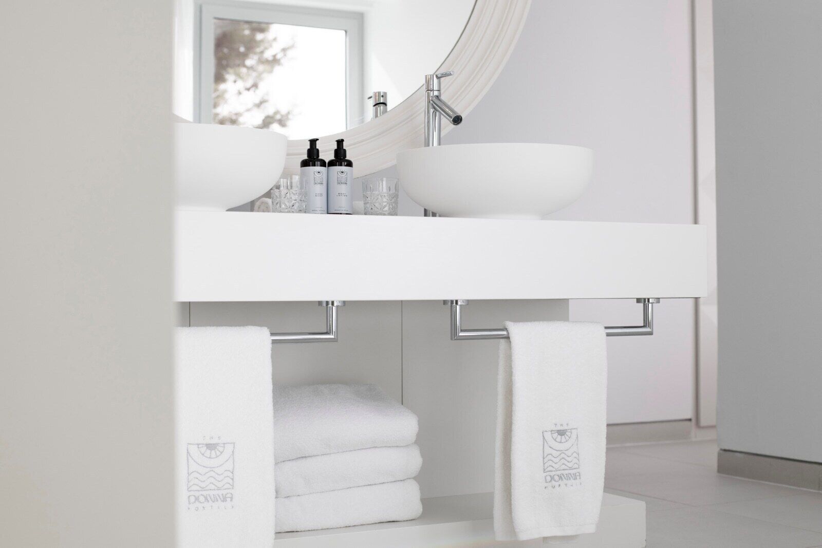 A modern bathroom with a white sink, a large mirror, and two towels hanging on towel bars.