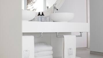 A modern bathroom with a white sink, a large mirror, and two towels hanging on towel bars.
