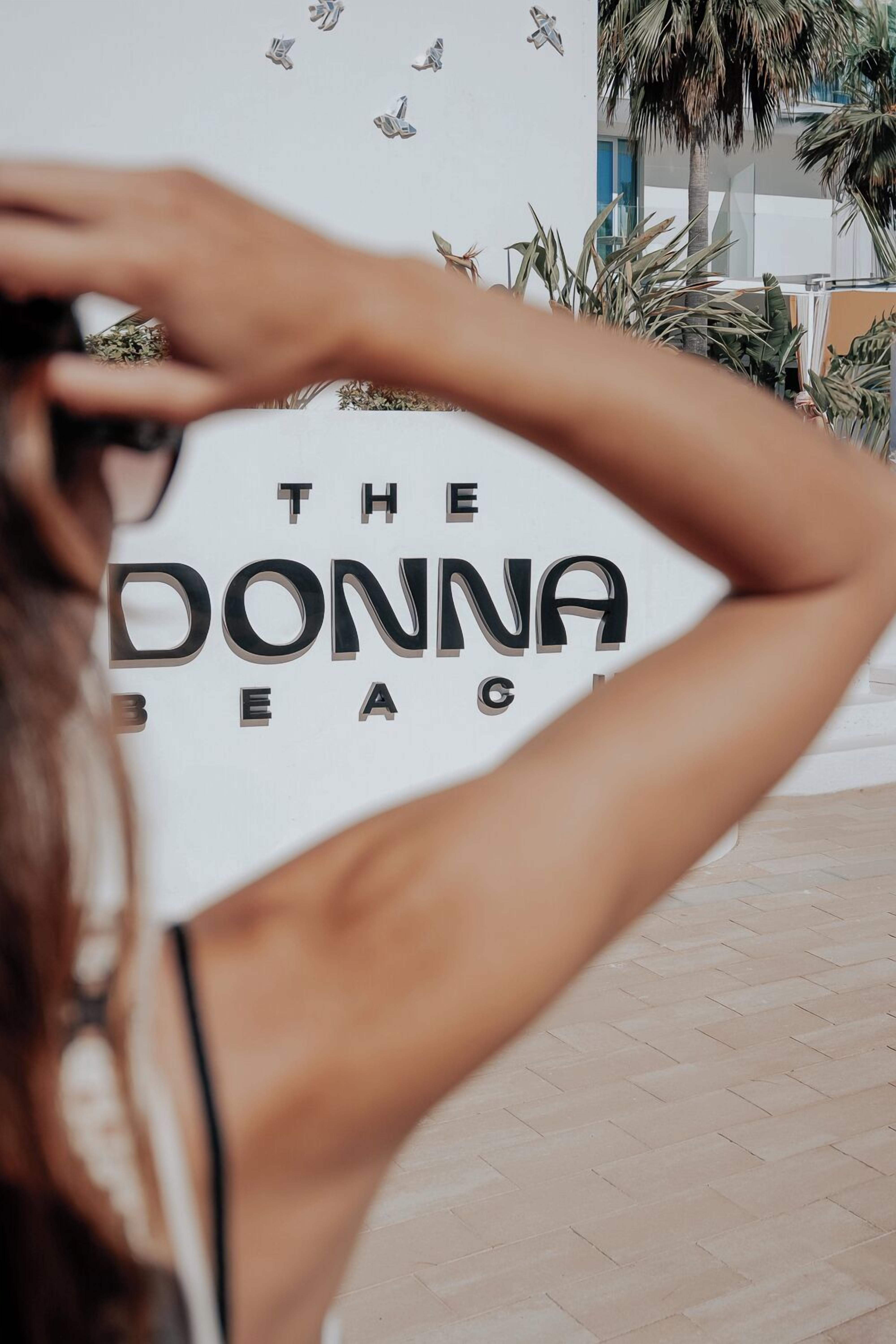 A sign with the text "THE DONNA BEACH CLUB" in a modern font.