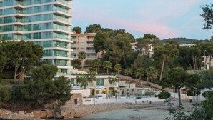 A modern hotel with multiple floors, surrounded by lush greenery and a hillside. - The Donna Portals (Calvia)