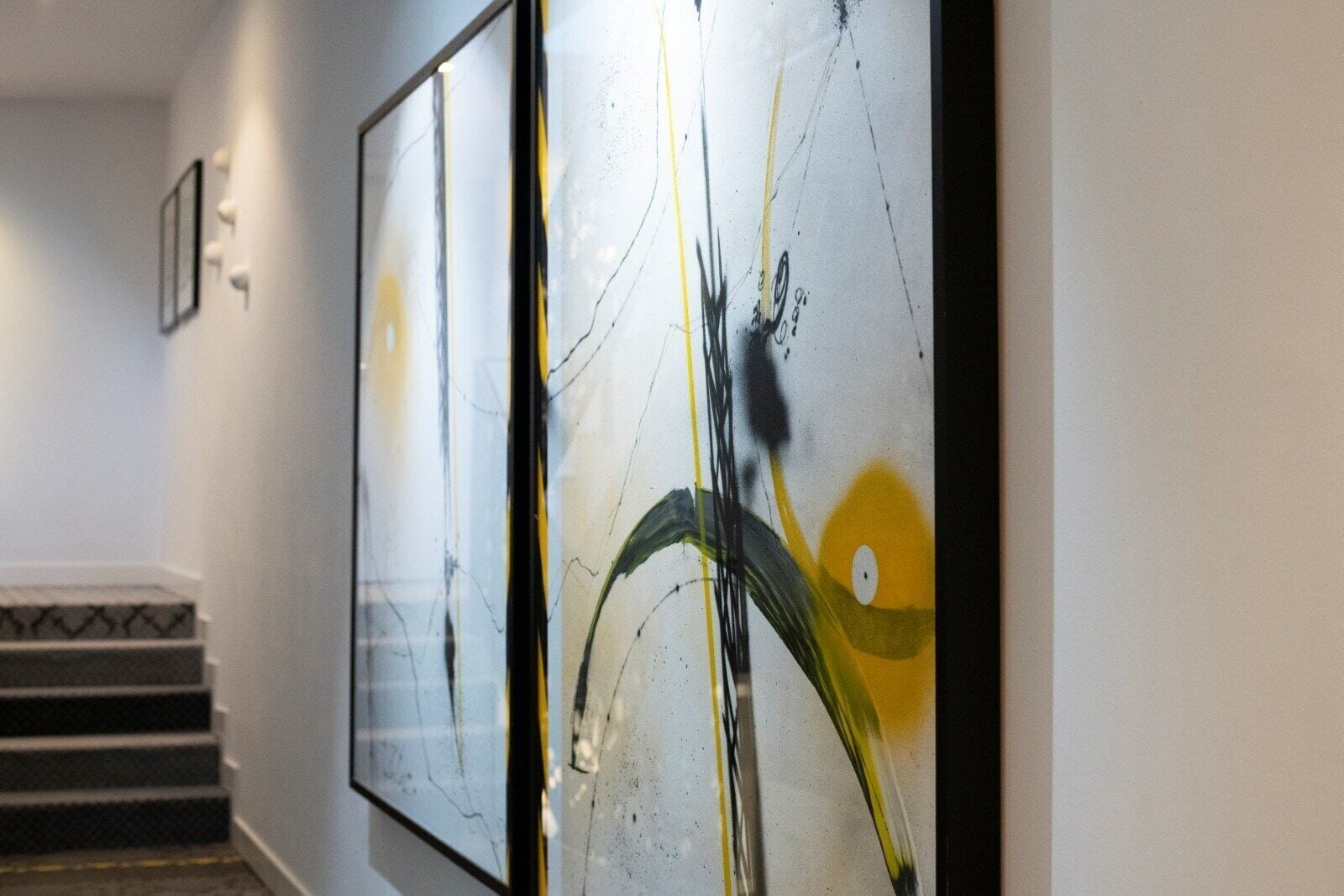 A hallway with abstract art on the walls and a staircase with patterned steps.