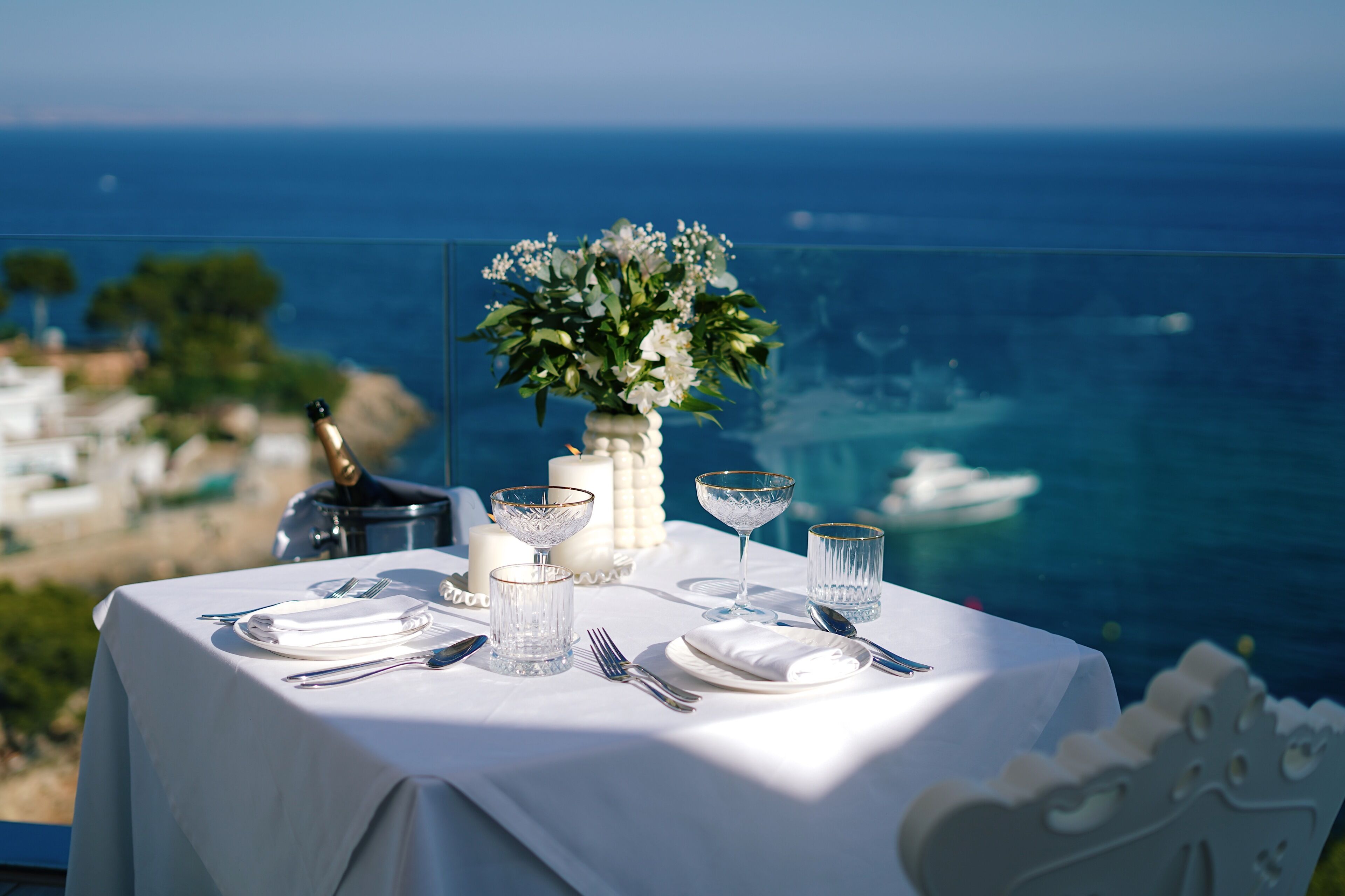 A table set for a meal with a view of the ocean and a coastal landscape.