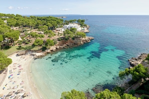 A coastal area with a beach, clear turquoise waters, and a rocky shoreline. - The Donna Portals (Calvia)