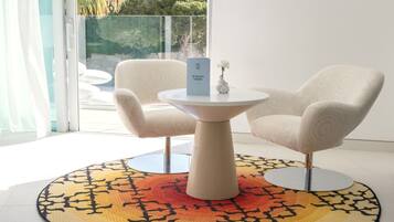 Una habitación moderna con una mesa redonda y dos sillas, una alfombra estampada y vistas al exterior con vegetación.
