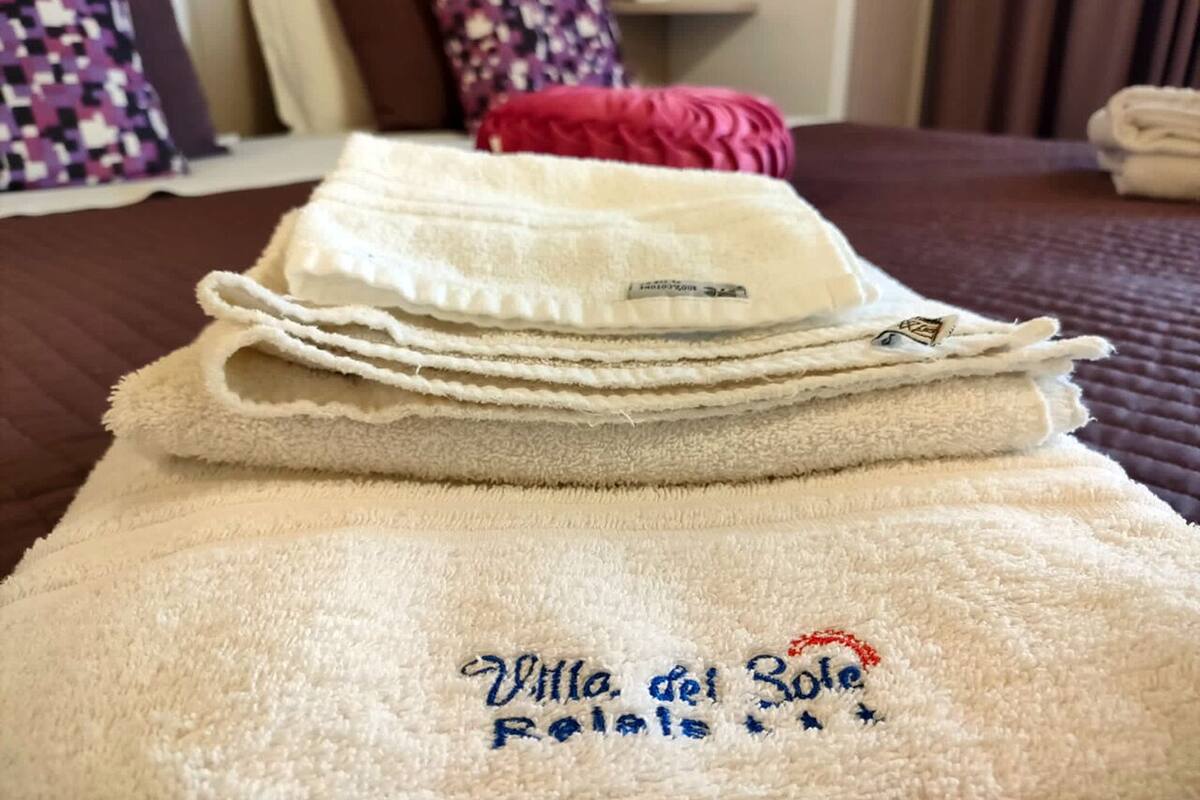 A neatly folded set of white towels with embroidered text on a bed.