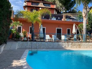 A pool area with a clear blue pool, lounge chairs, and a building with balconies. - Villa del Sole Relais (Agrigento)