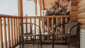 Una terraza de madera con dos sillas de metal y una mesa.