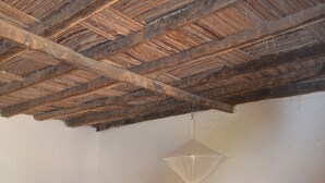 A bedroom with a wooden bed, a small table, and a hanging light fixture. - Oudja Hotel (Cap Skirring)