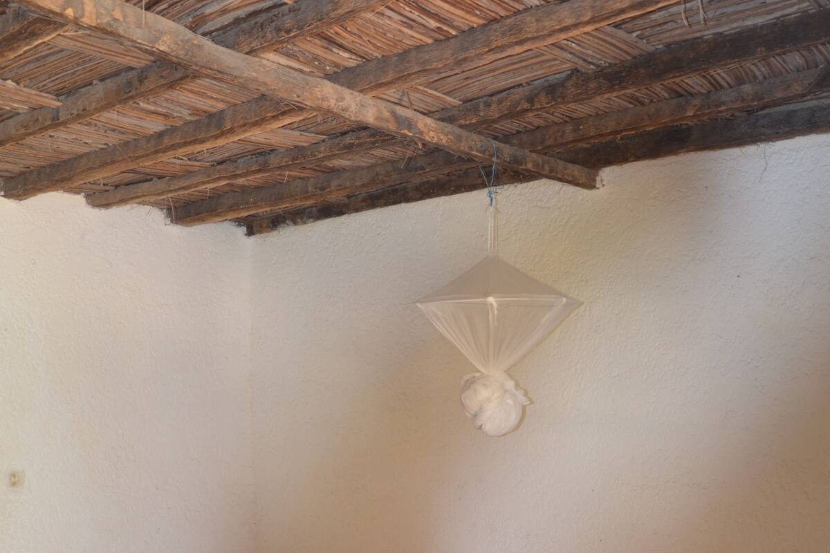 Un dormitorio con cama de madera, una mesita pequeña y una lámpara colgante.