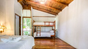 Een kamer met een houten plafond, een stapelbed, een enkel bed en een deur die naar buiten leidt.
