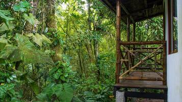 Una estructura de madera con armazón de bambú, rodeada de exuberante follaje tropical.