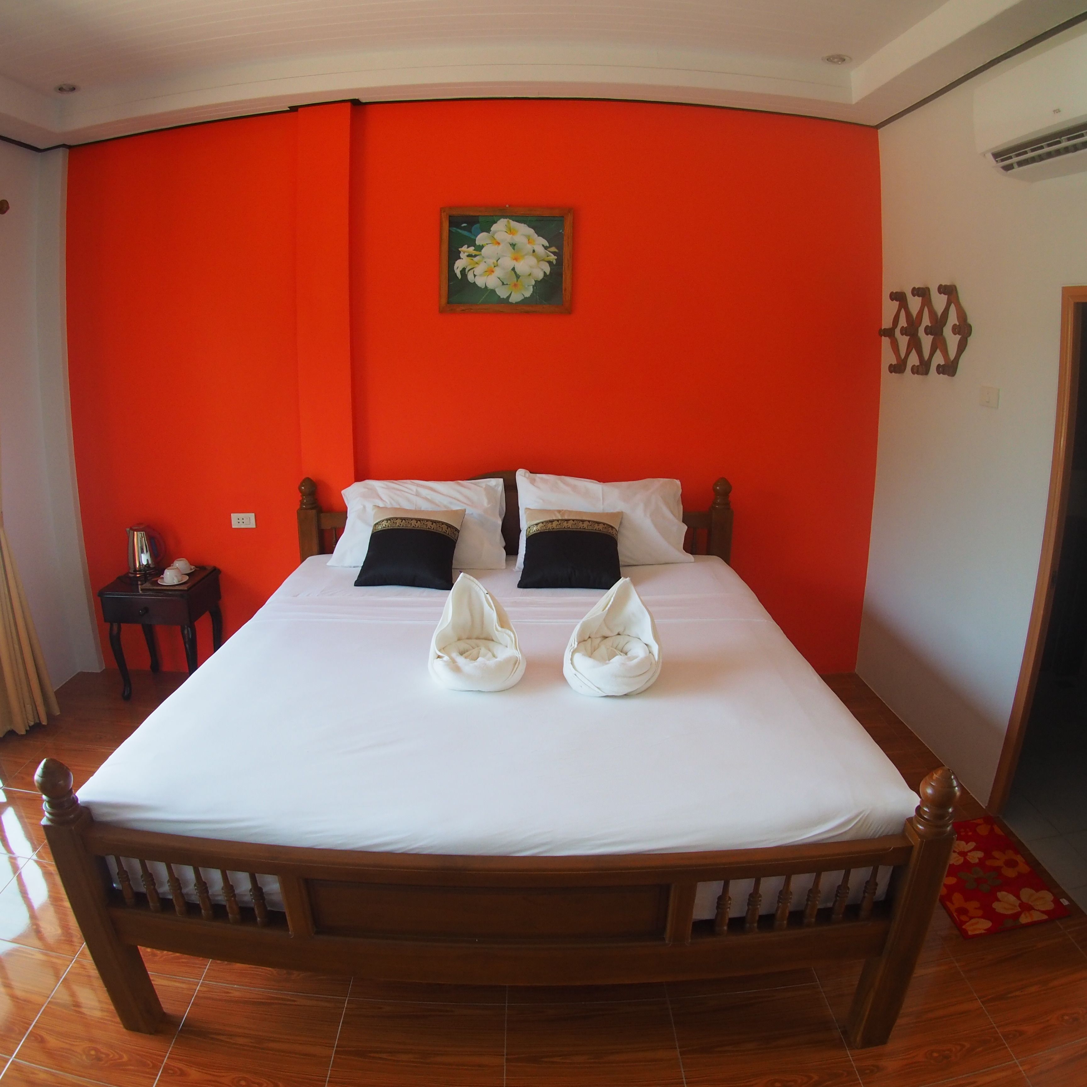 Una habitación de hotel con una cama grande, una mesita de noche pequeña y una pared de acento roja.