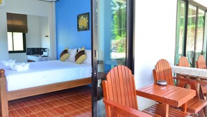 Une chambre avec un lit, un petit coin cuisine et une vue sur la verdure grâce à une porte vitrée.