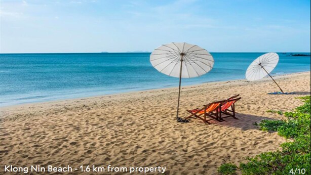 Une plage avec deux parasols blancs et une chaise de plage, située à 1,6 km d’un établissement.