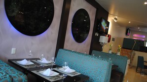 Un restaurante con espejos redondos, asientos tipo cabina con estampado azul y una decoración interior moderna.