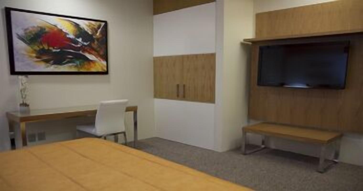 Une salle de conférence équipée d’une grande table, d’un téléviseur fixé au mur et d’un meuble en bois.