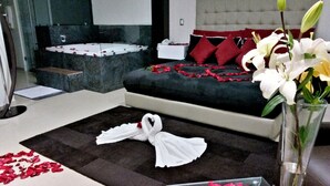 Una habitación de hotel con cama, mesita de noche, espejo y un florero con flores.