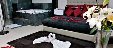A hotel room with a bed, a bedside table, a mirror, and a vase with flowers.