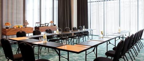 A conference room with long tables, chairs, and a projector screen.