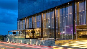 Um edifício moderno com grandes janelas, uma entrada bem iluminada e um letreiro de restaurante visível.