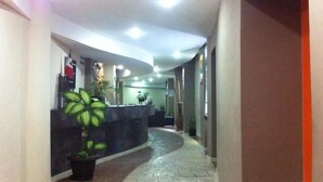 A hotel reception area with a curved reception desk, a potted plant, and a tiled floor. - Hotel & Suites Domani (Progreso)